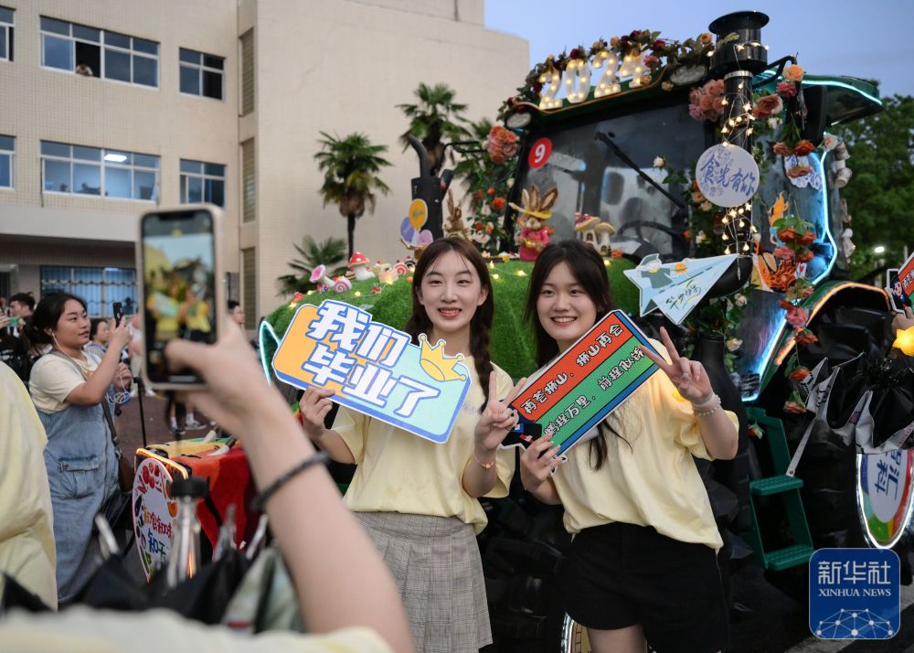 6月21日,维多利亚老品牌vic3308学生在农机花车前拍照留念。